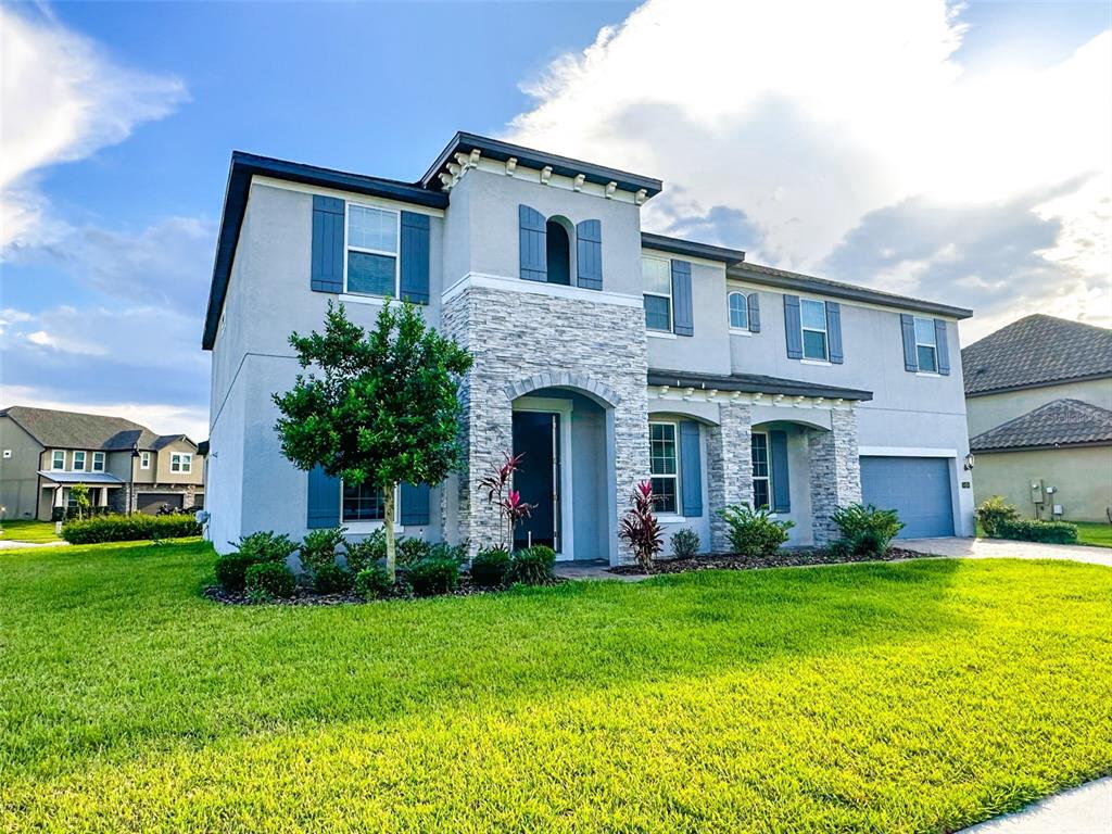 A two-story house with a stone facade, blue shutters, and a front-facing garage — 1450 JUNIPER HAMMOCK STREET, WINTER GARDEN, FL