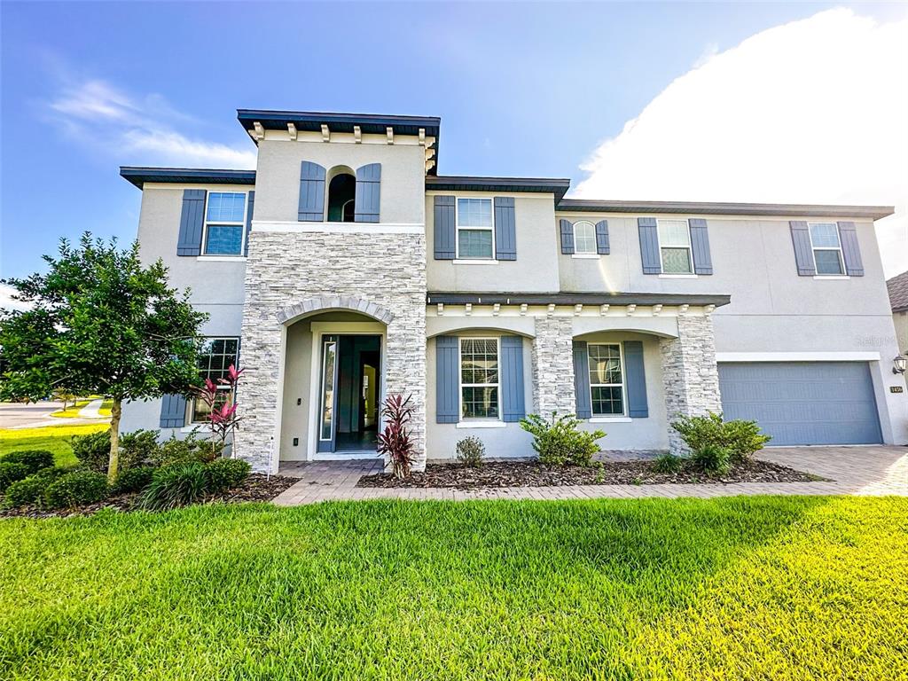 A two-story house with a stone facade, blue shutters, and a two-car garage — 1450 JUNIPER HAMMOCK STREET, WINTER GARDEN, FL