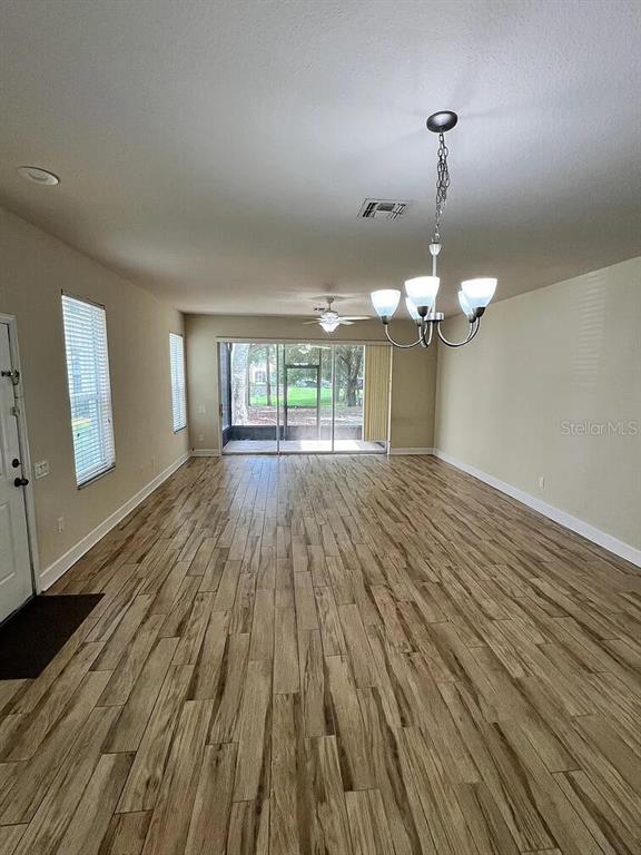An empty living area with wood-look tile flooring, a chandelier, and sliding glass doors — 6058 TWAIN STREET UNIT 101, ORLANDO, FL