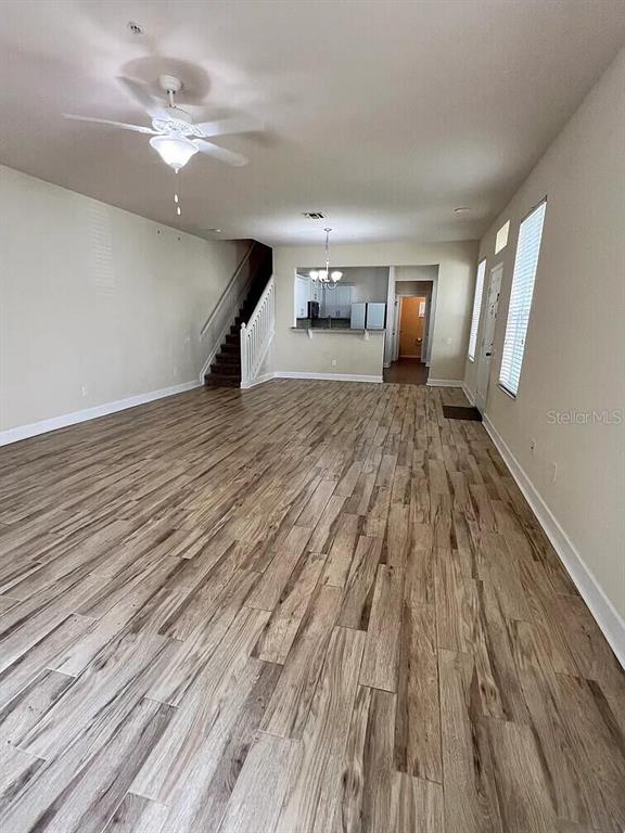 An open-concept living area features wood-look flooring, a ceiling fan, and a staircase — 6058 TWAIN STREET UNIT 101, ORLANDO, FL