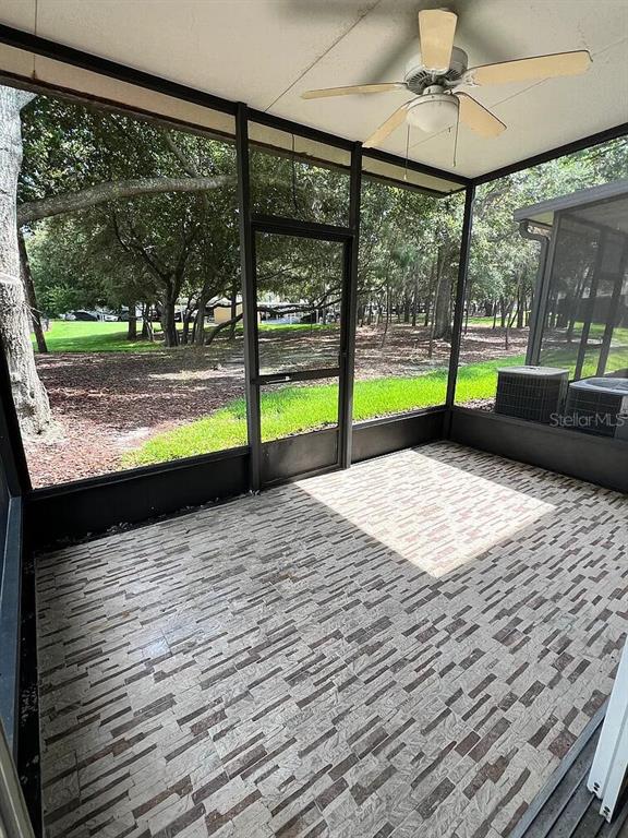 A screened-in porch features a ceiling fan, tiled flooring, and views of a wooded yard — 6058 TWAIN STREET UNIT 101, ORLANDO, FL
