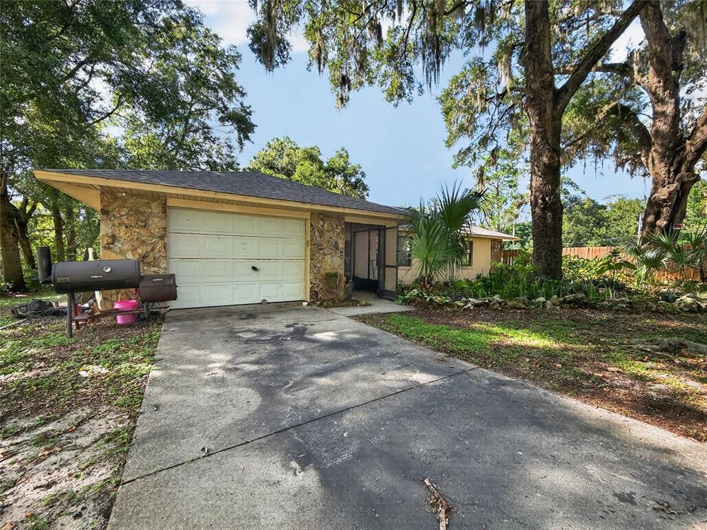 A single-story house with a stone facade, a white garage door, and a concrete driveway — 11025 SE 132ND PLACE, OCKLAWAHA, FL