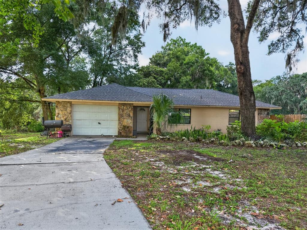 A single-story house with a stone facade, a white garage door, and a concrete driveway — 11025 SE 132ND PLACE, OCKLAWAHA, FL