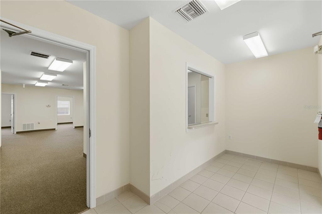 A tiled reception area with a service window opens into a carpeted office space — 4390 NE 35TH STREET UNIT 2, OCALA, FL