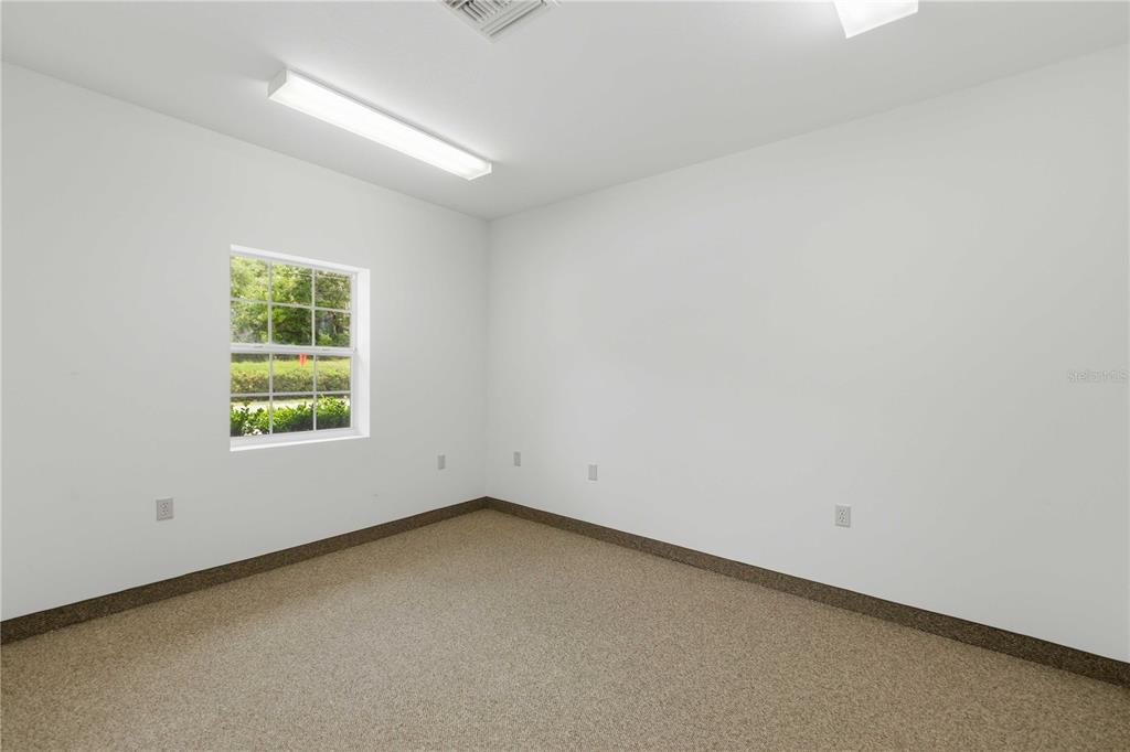 An empty room with white walls, beige carpeting, a single window, and fluorescent lighting — 4390 NE 35TH STREET UNIT 2, OCALA, FL