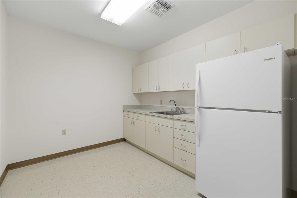 A small kitchen features white cabinets, a sink, and a white refrigerator — 4390 NE 35TH STREET UNIT 2, OCALA, FL