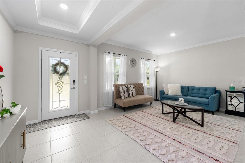 A bright living room features a blue sofa, a beige settee, and a patterned rug — 218 SW CADENCE GLEN, LAKE CITY, FL