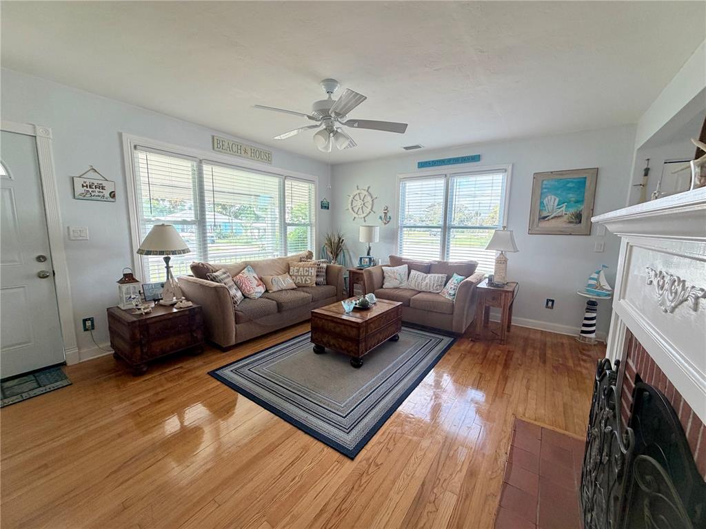 A living room with hardwood floors, two brown sofas, a coffee table, and beach-themed decor — 231 WILLIAMS AVENUE, DAYTONA BEACH, FL