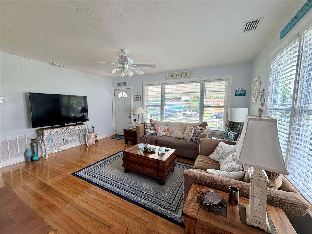 A living room with hardwood floors, a large television, and coastal-themed decor — 231 WILLIAMS AVENUE, DAYTONA BEACH, FL