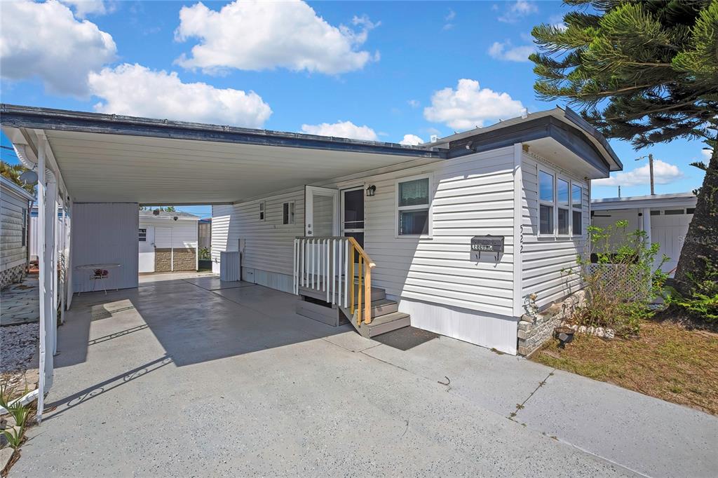 A white mobile home features a concrete carport, a small wooden staircase, and a mailbox — 770 32ND AVENUE S UNIT 522, ST PETERSBURG, FL