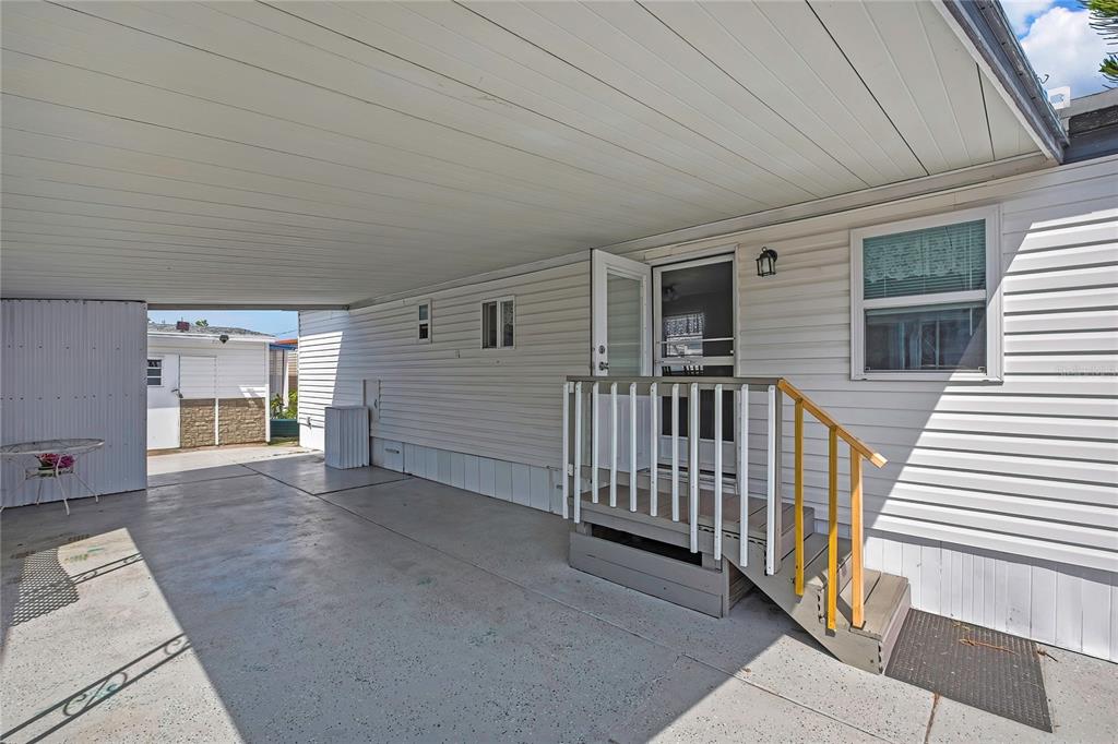 A white mobile home exterior features a covered carport, concrete patio, and small wooden stairs — 770 32ND AVENUE S UNIT 522, ST PETERSBURG, FL
