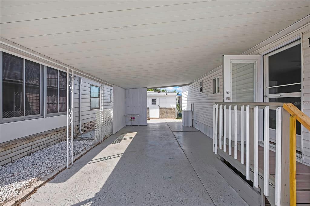 A covered carport area sits between a mobile home and a small detached shed — 770 32ND AVENUE S UNIT 522, ST PETERSBURG, FL
