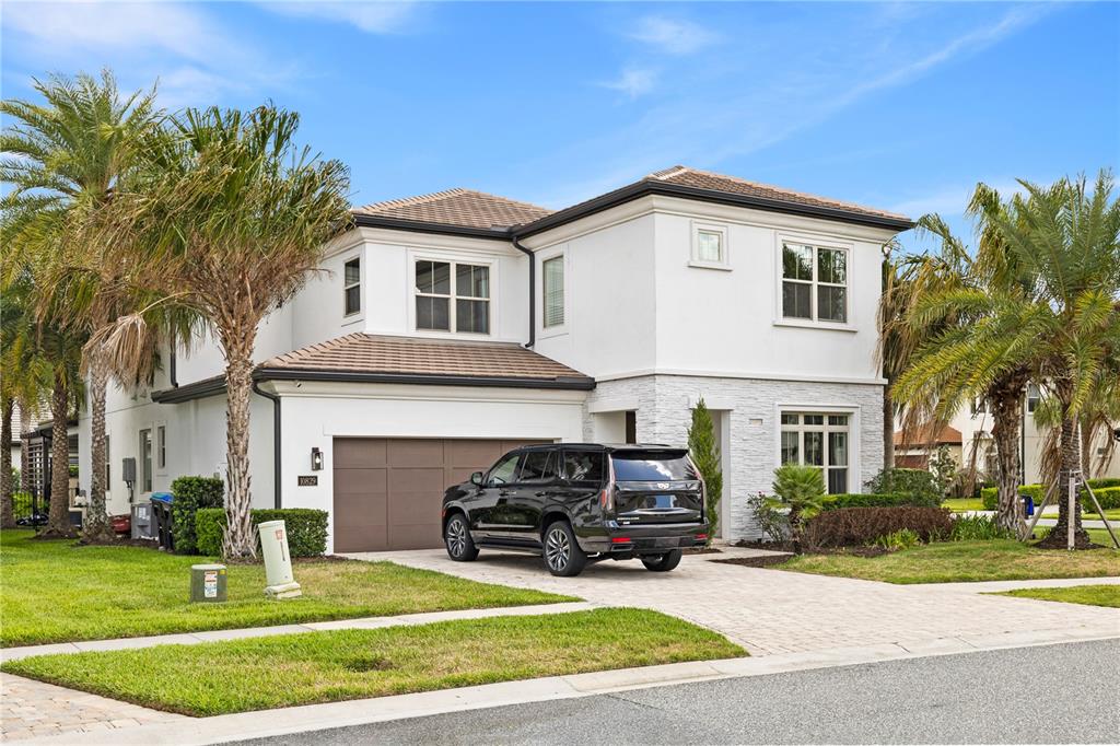 A two-story white house with a stone facade, a brown garage, and palm trees — 10829 ROYAL CYPRESS WAY, ORLANDO, FL