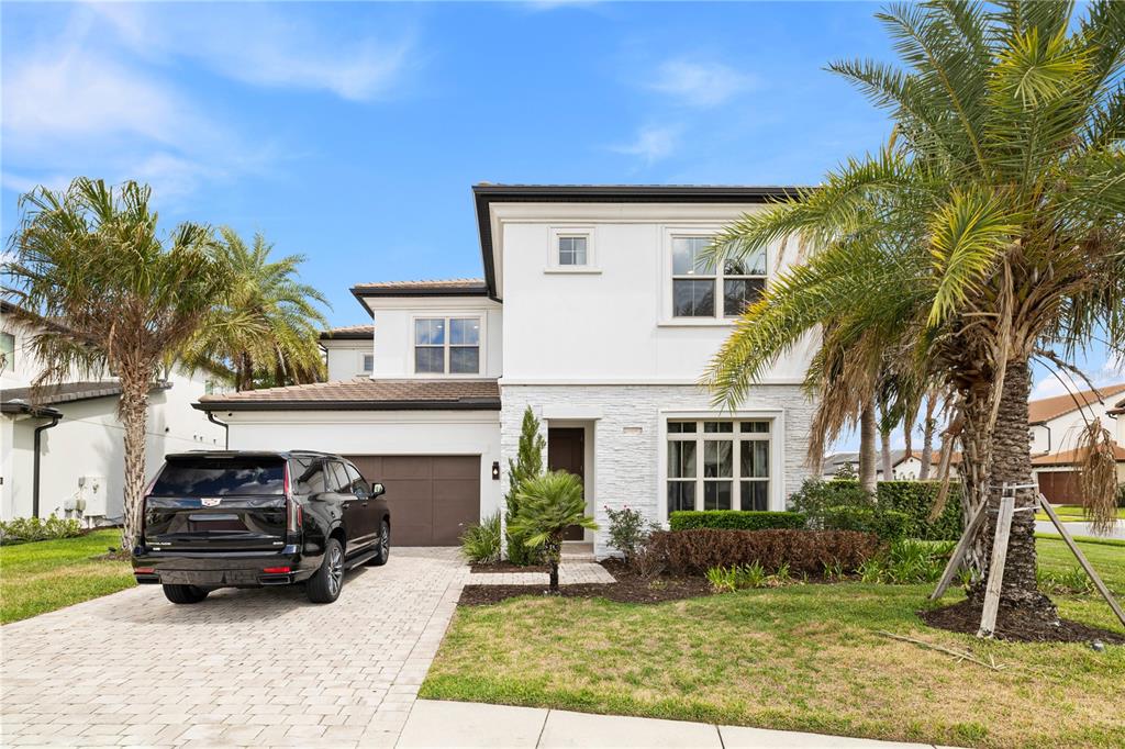 A two-story house with a white facade, stone accents, and a black SUV in the driveway — 10829 ROYAL CYPRESS WAY, ORLANDO, FL