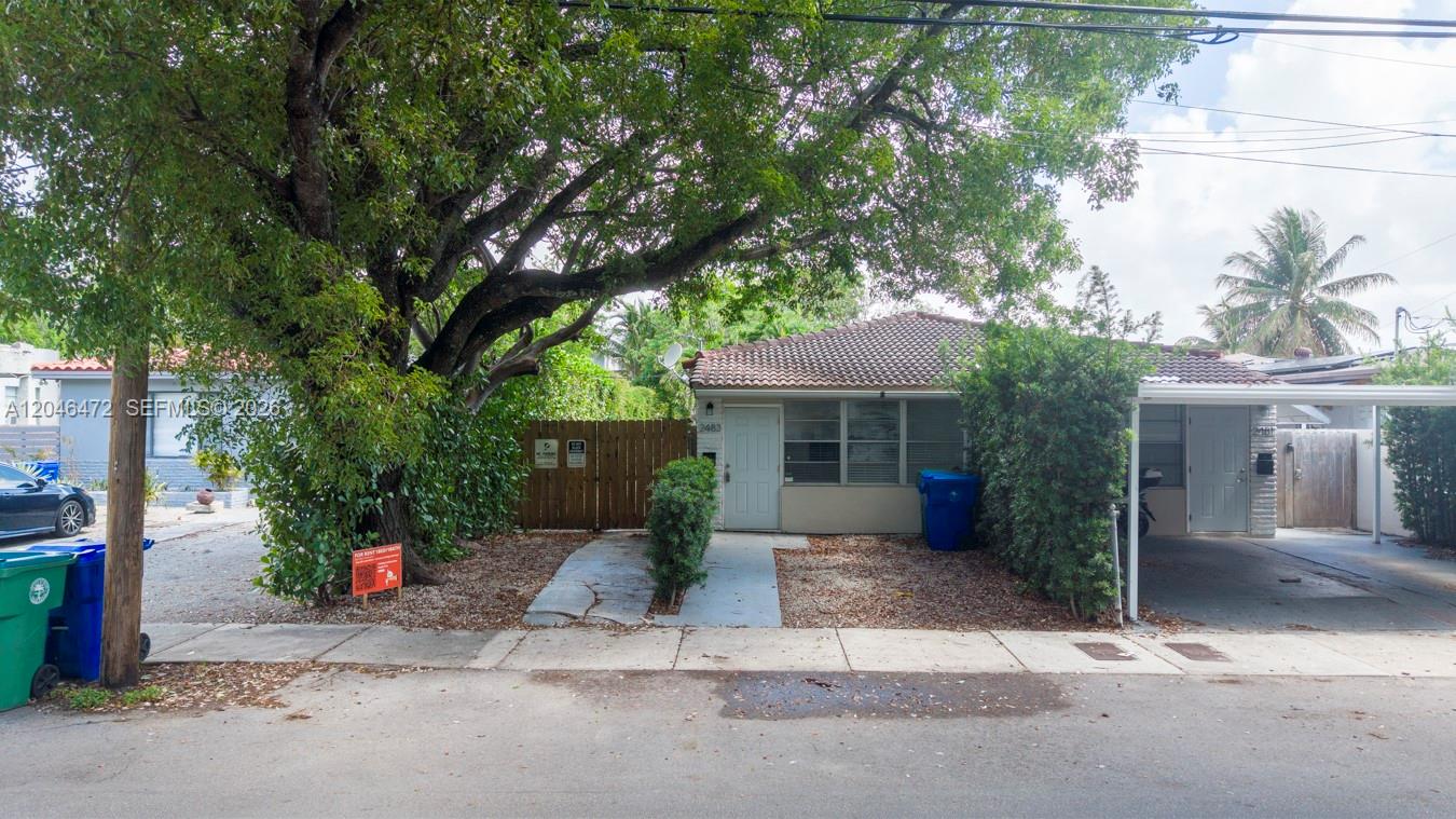 A single-story house with a tiled roof, a carport, and a large tree in front — MIAMI, FL