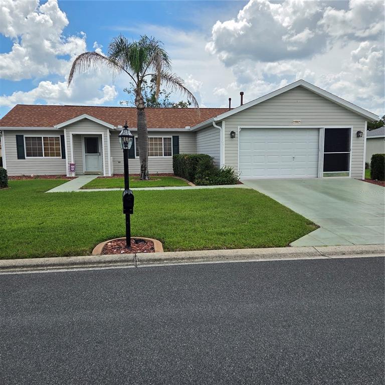 A single-story house with light siding, a two-car garage, and a palm tree in front — 13902 SE 85TH COURT, SUMMERFIELD, FL