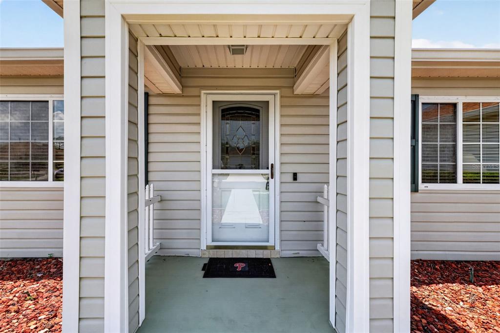 The exterior view shows a covered front porch with a storm door and beige siding — 13902 SE 85TH COURT, SUMMERFIELD, FL