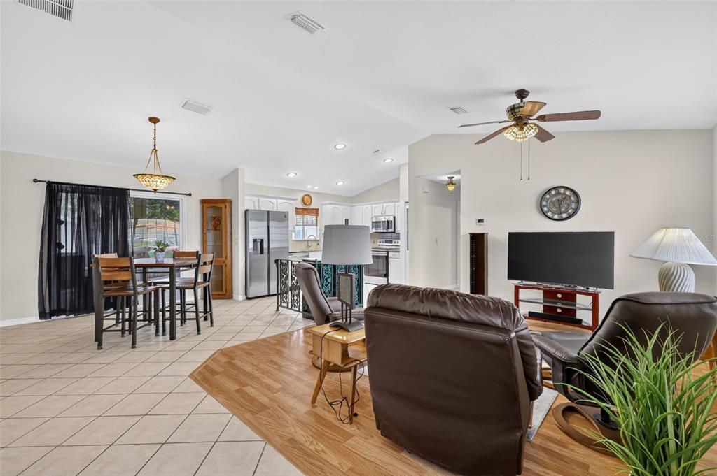 An open-concept living and dining area features tile and wood flooring, a ceiling fan, and kitchen — 13902 SE 85TH COURT, SUMMERFIELD, FL