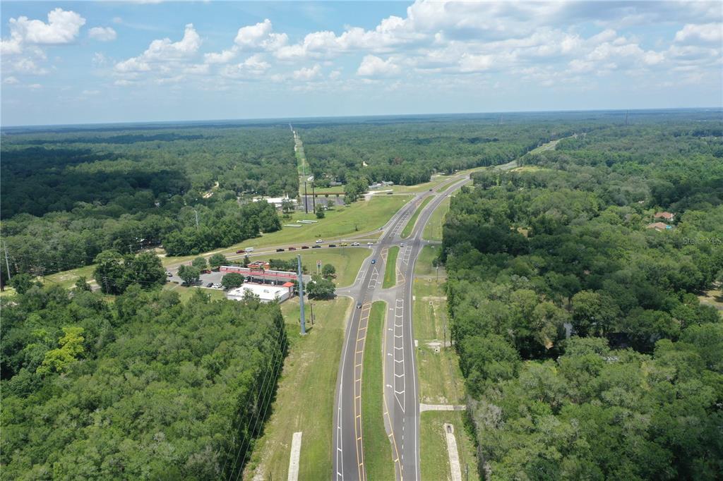 An aerial view shows a highway intersection surrounded by dense forest and a gas station — 2745 POINSETTIA AVENUE, MIDDLEBURG, FL