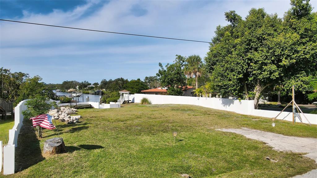 A grassy, fenced waterfront lot features an American flag and a small wooden structure — 223 RAVENNA STREET, NOKOMIS, FL