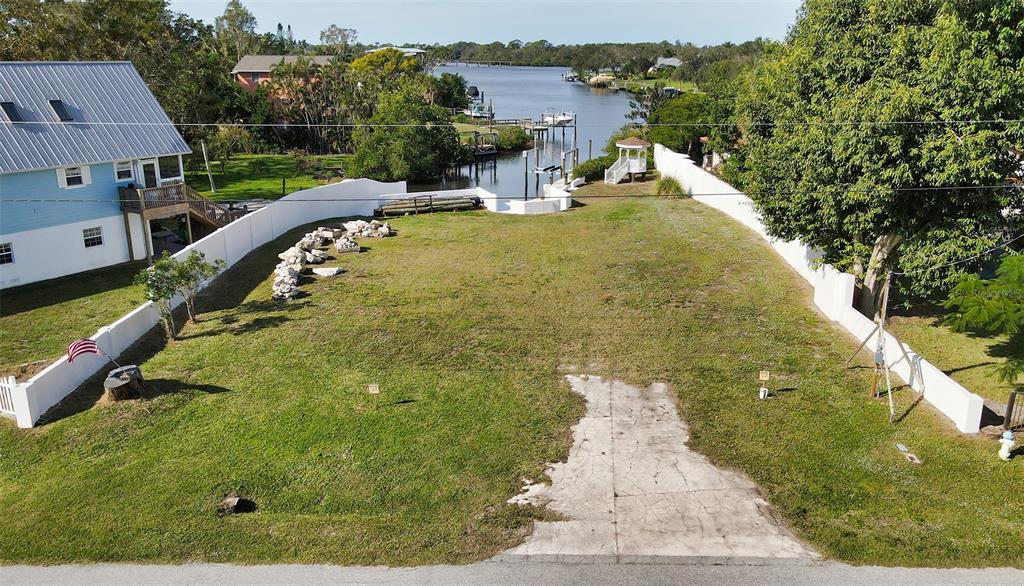 An elevated view of a vacant waterfront lot with a concrete driveway and white fencing — 223 RAVENNA STREET, NOKOMIS, FL
