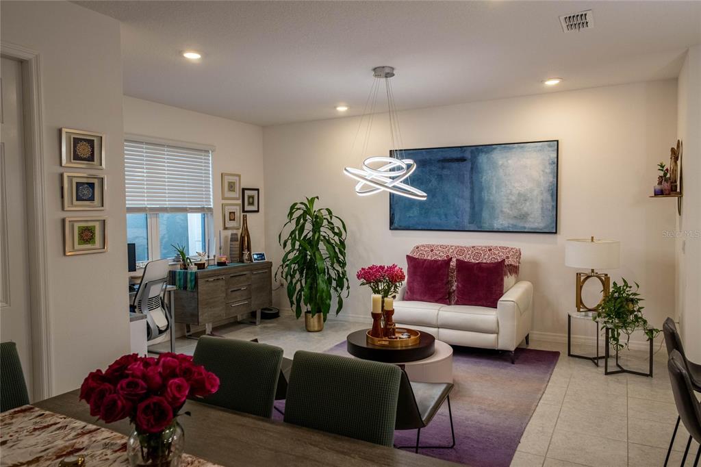 A living and dining area features a white sofa, modern light fixture, and blue wall art — 5222 FERNDALE ALLEY, ST CLOUD, FL
