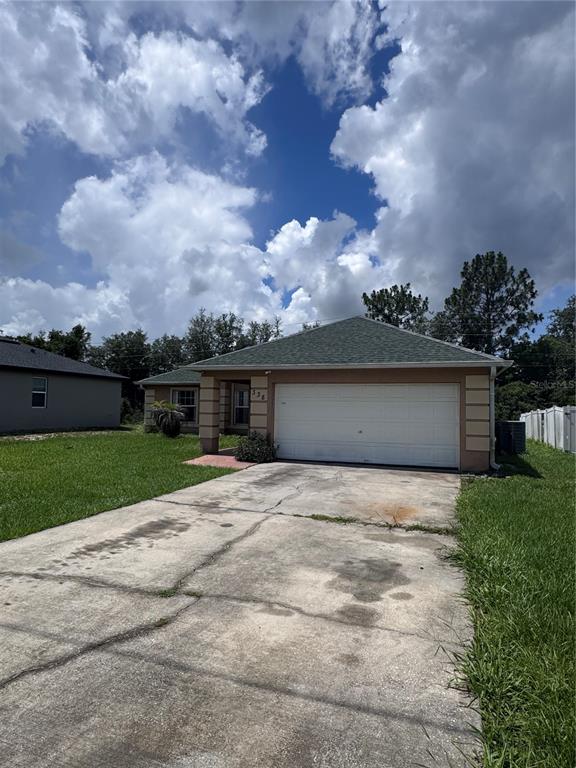 A single-story house with a white garage door, beige stucco exterior, and a concrete driveway — 338 KINGFISH DRIVE, KISSIMMEE, FL