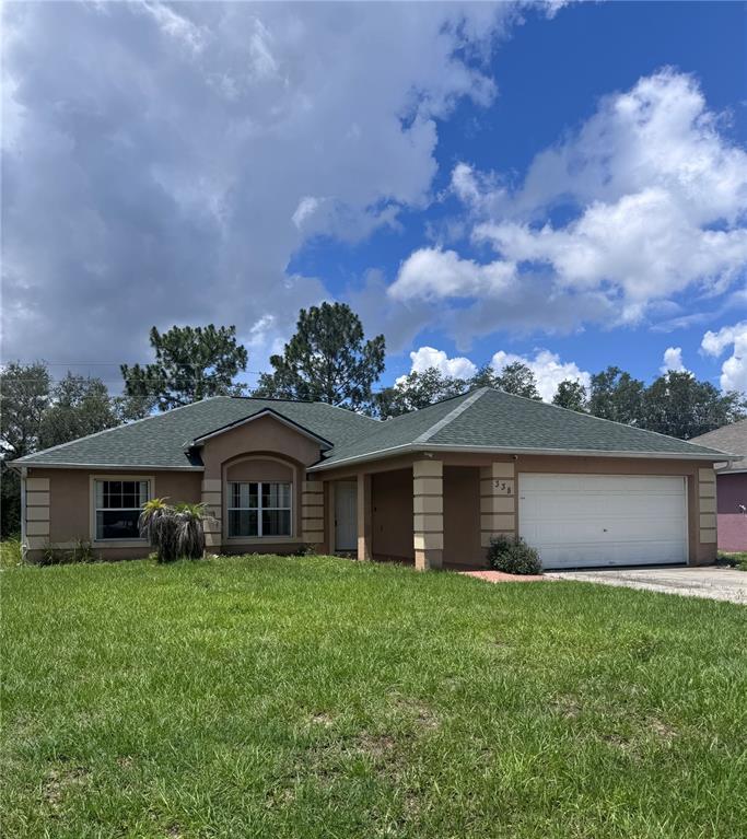 A single-story house with a tan stucco exterior, green roof, and two-car garage — 338 KINGFISH DRIVE, KISSIMMEE, FL