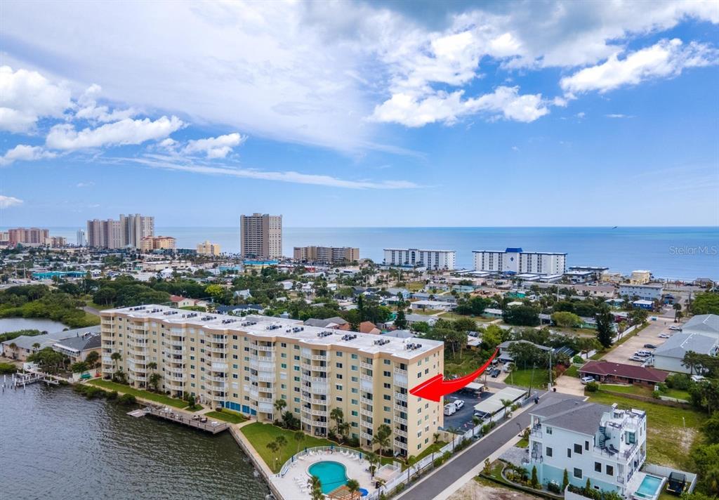 An aerial view of a multi-story apartment building with a pool next to the water — 3606 S PENINSULA DRIVE UNIT 614, PORT ORANGE, FL