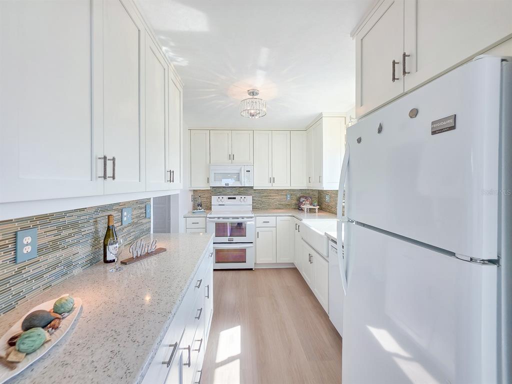 A white kitchen features light countertops, a tiled backsplash, and a white refrigerator — 3606 S PENINSULA DRIVE UNIT 614, PORT ORANGE, FL