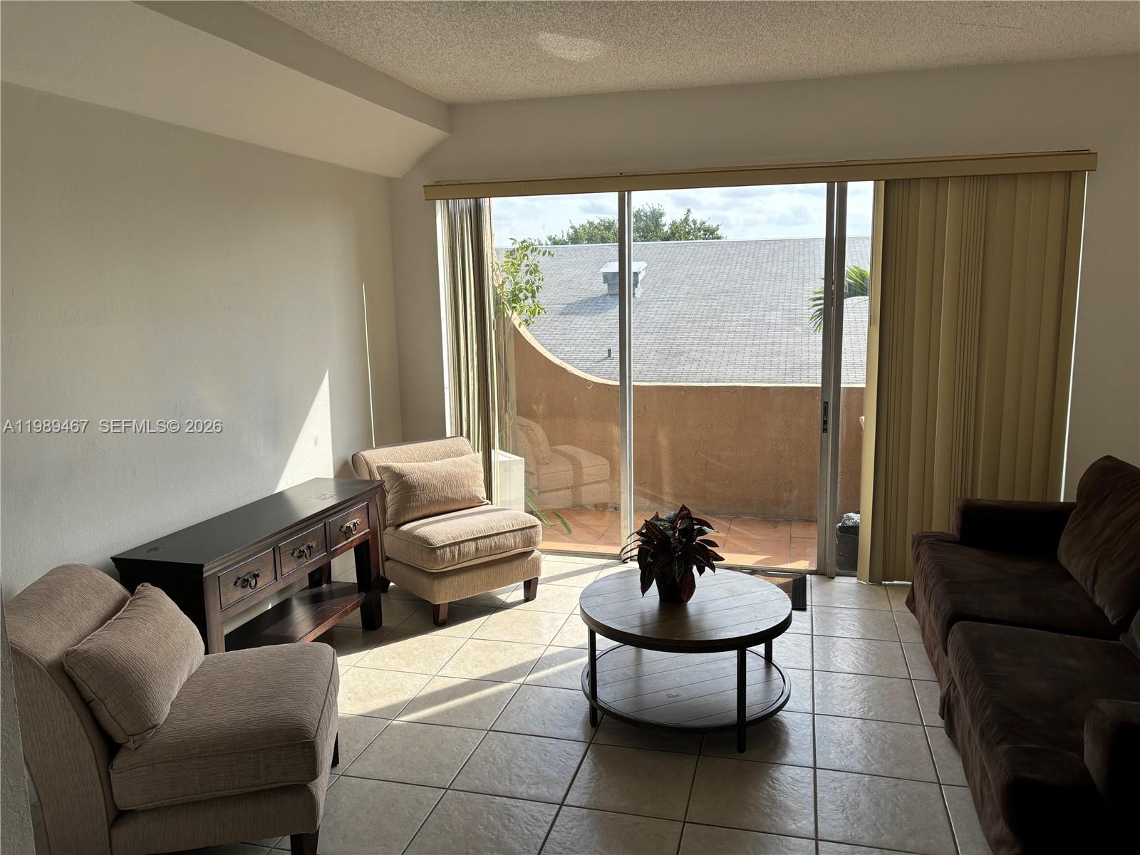 A living room features tile floors, a dark wood console, and a sliding glass door — 10900 SW 104th St # 303, Miami FL 33176, MIAMI, FL