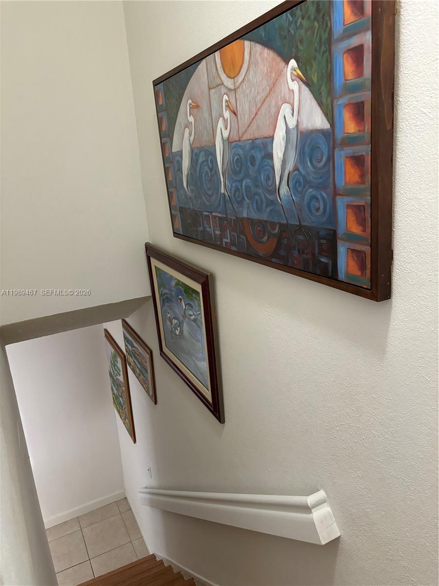 A staircase features a white handrail and several framed paintings hanging on the wall — 10900 SW 104th St # 303, Miami FL 33176, MIAMI, FL