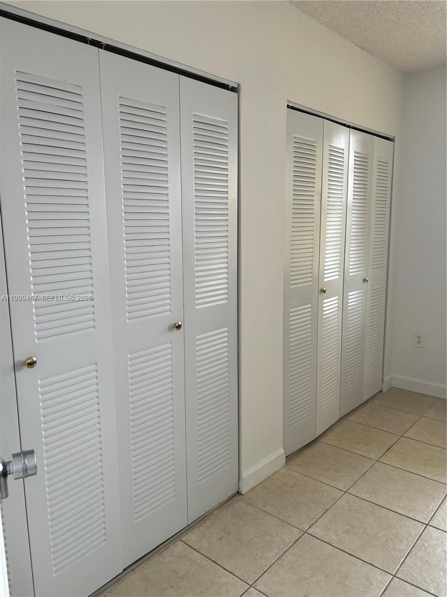 Two sets of white louvered closet doors are installed along a wall with tiled flooring — 10900 SW 104th St # 303, Miami FL 33176, MIAMI, FL