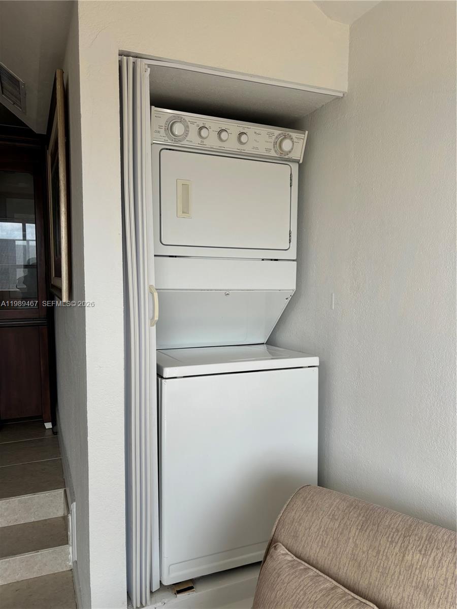 A white stacked washer and dryer unit is installed in a small closet alcove — 10900 SW 104th St # 303, Miami FL 33176, MIAMI, FL