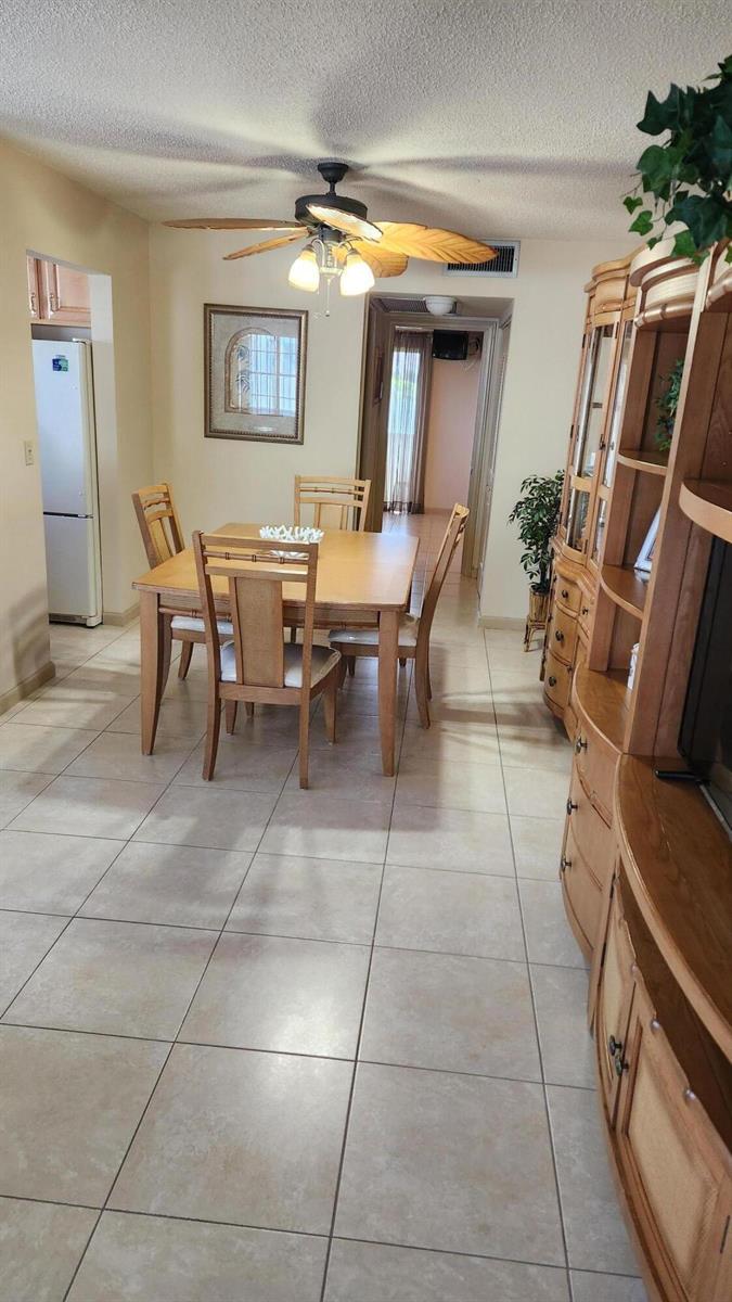 A dining area features a wooden table and chairs, tile flooring, and a ceiling fan — 96 Andover D, West Palm Beach FL 33417, WEST PALM BEACH, FL