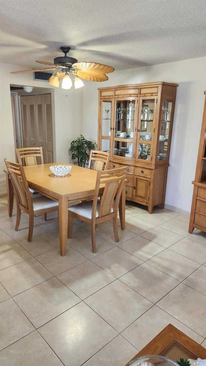 A dining room featuring a wooden table, four chairs, a matching hutch, and tile flooring — 96 Andover D, West Palm Beach FL 33417, WEST PALM BEACH, FL
