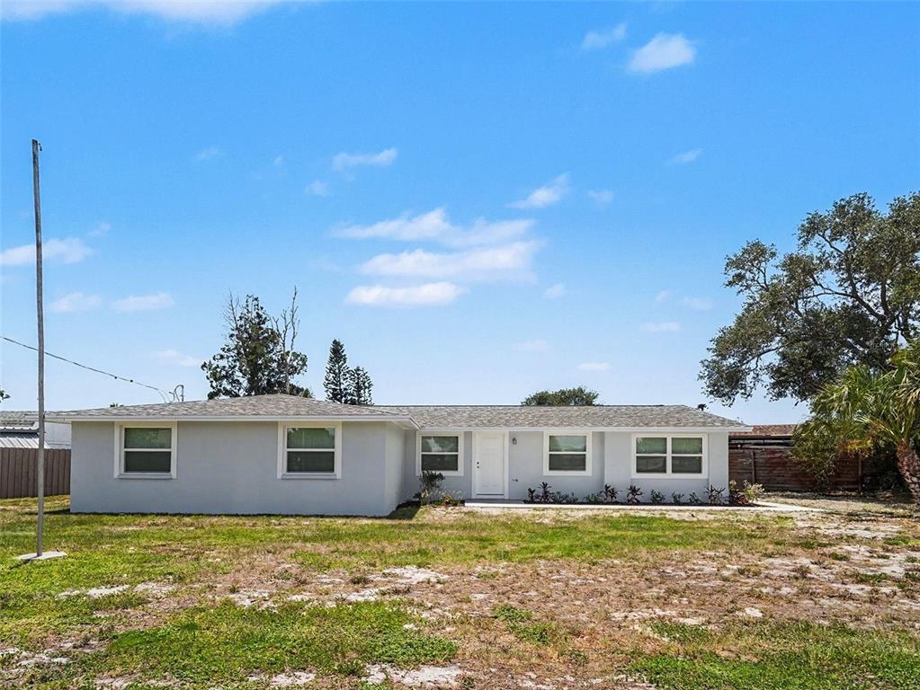 A single-story, light gray house with a shingled roof sits on a grassy lot — 802 WHITE HERON BOULEVARD, RUSKIN, FL
