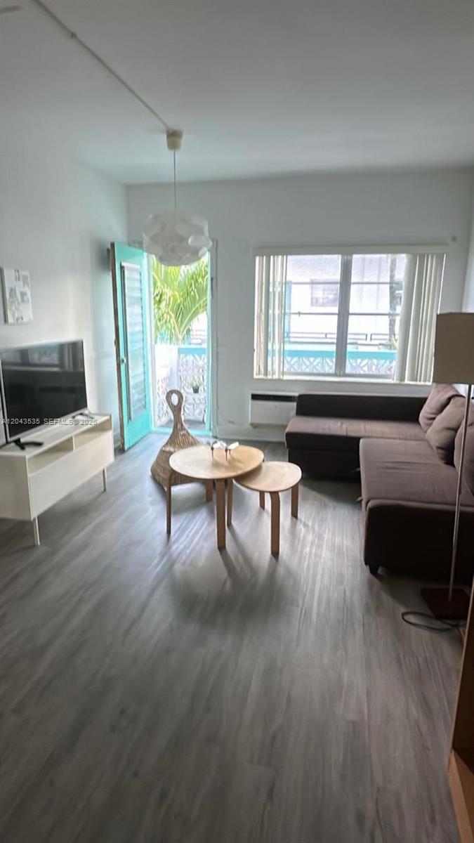 A living room features gray wood-look flooring, a brown sectional sofa, and a turquoise door — 6498 Collins Ave # 48, Miami Beach FL 33141, MIAMI BEACH, FL