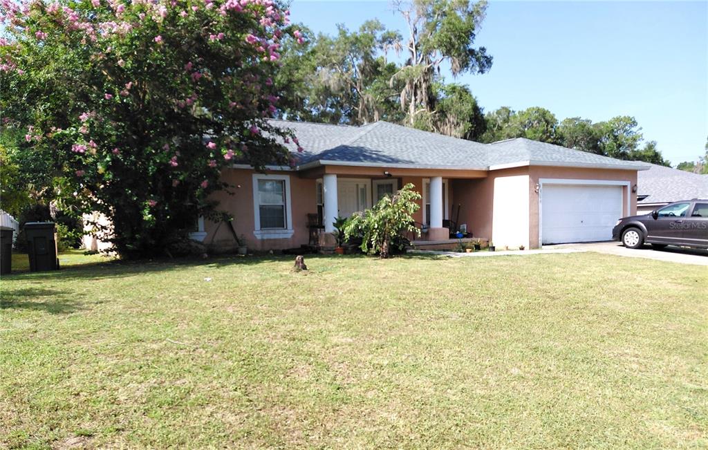 A single-story house with a tan stucco exterior, a gray shingled roof, and a two-car garage — 2716 NE 24TH PLACE, OCALA, FL