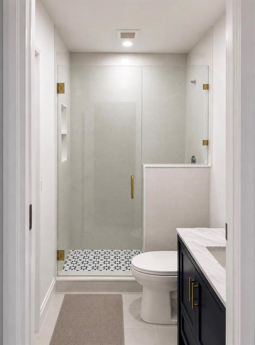 A modern bathroom features a glass-enclosed shower with patterned floor tiles and a dark vanity — 7971 Chula Vista Crescent, Boca Raton FL 33433, BOCA RATON, FL