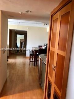 A hallway with wood flooring leads to a dining area with a wooden table — 1688 West Ave # 405, Miami Beach FL 33139, MIAMI BEACH, FL