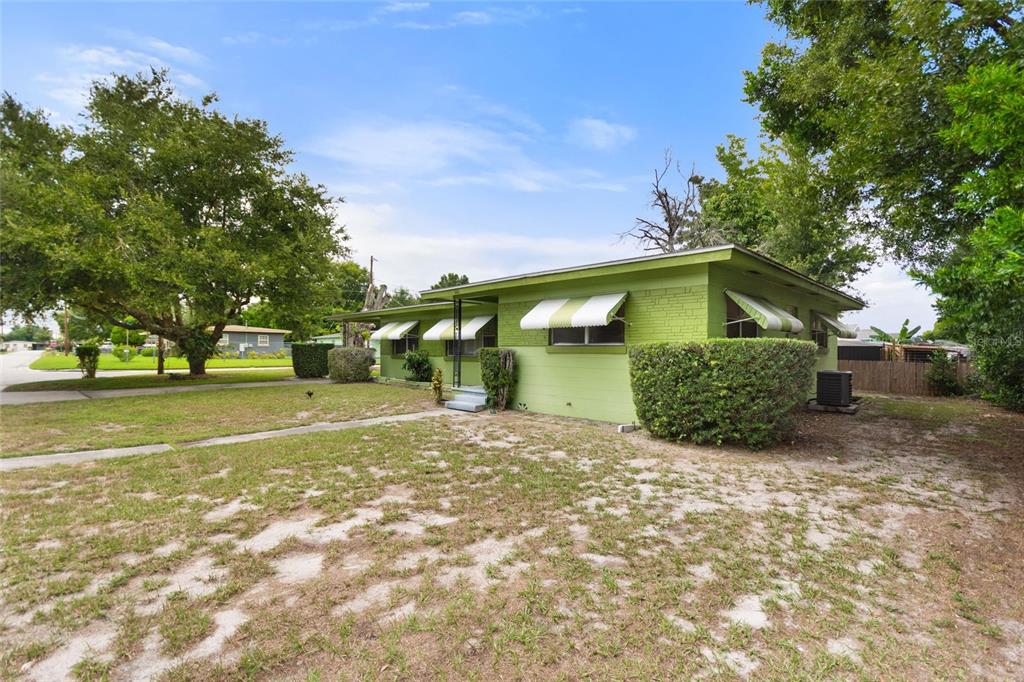 A lime green single-story house with striped window awnings sits on a grassy lot — 601 AVENUE U NE, WINTER HAVEN, FL