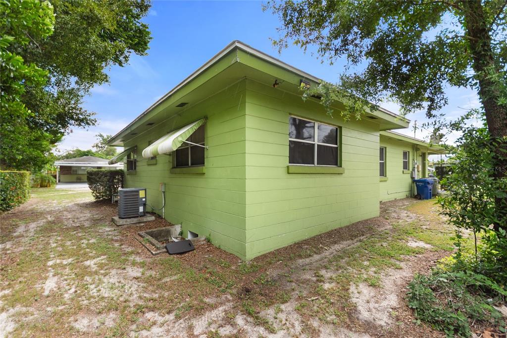 The exterior of a lime green concrete block house with a striped window awning — 601 AVENUE U NE, WINTER HAVEN, FL