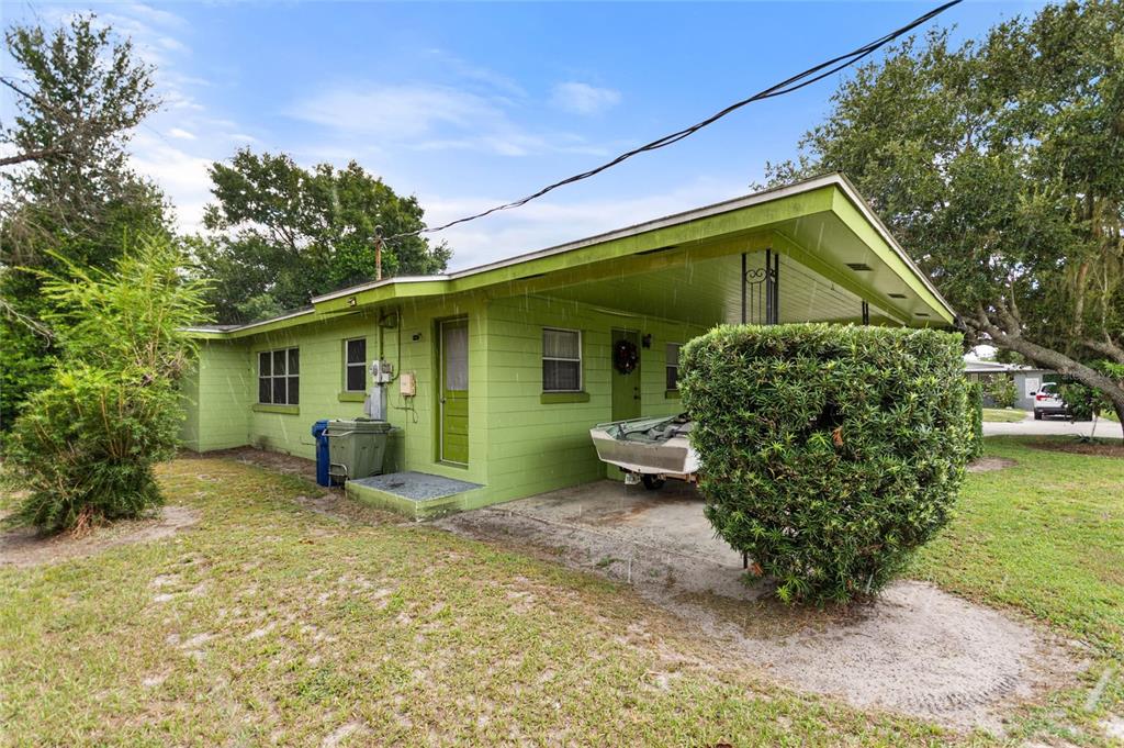 A light green concrete block house features a carport, a small boat, and landscaping — 601 AVENUE U NE, WINTER HAVEN, FL