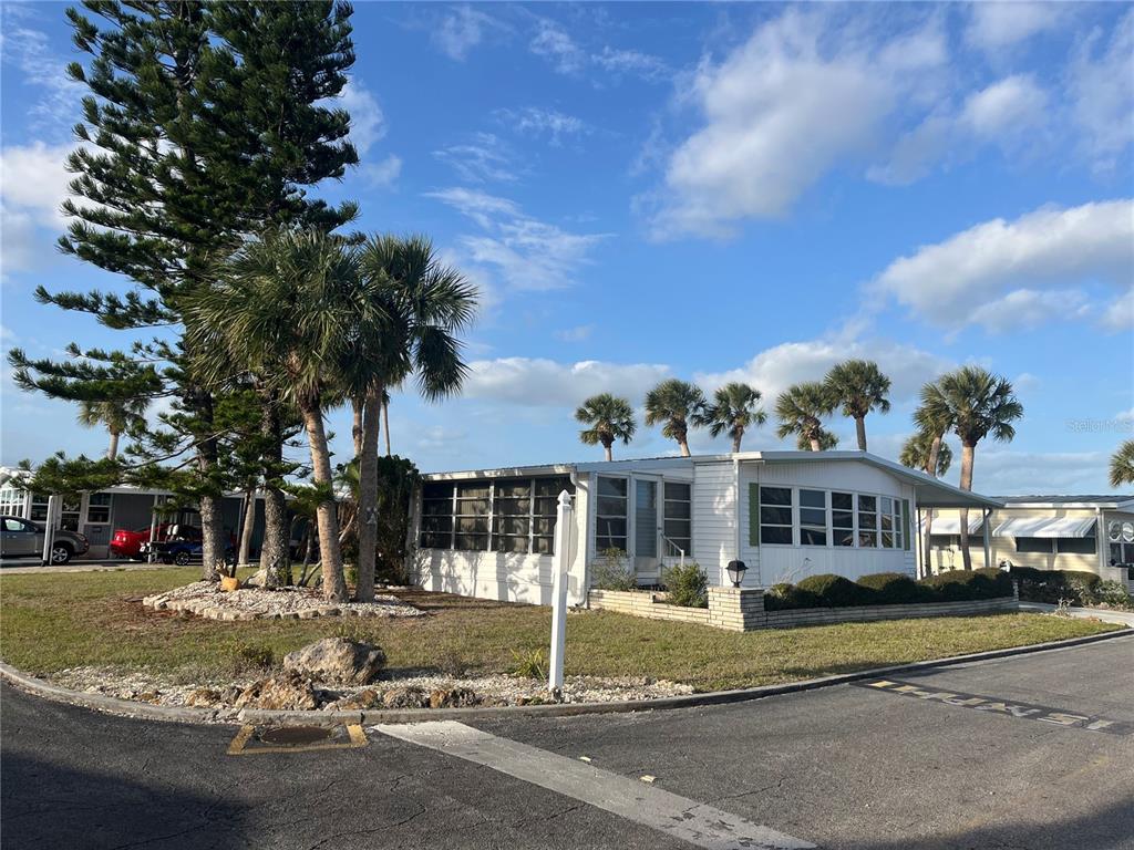 A white mobile home with a screened porch sits on a corner lot with palm trees — 532 VIA VENETO, VENICE, FL