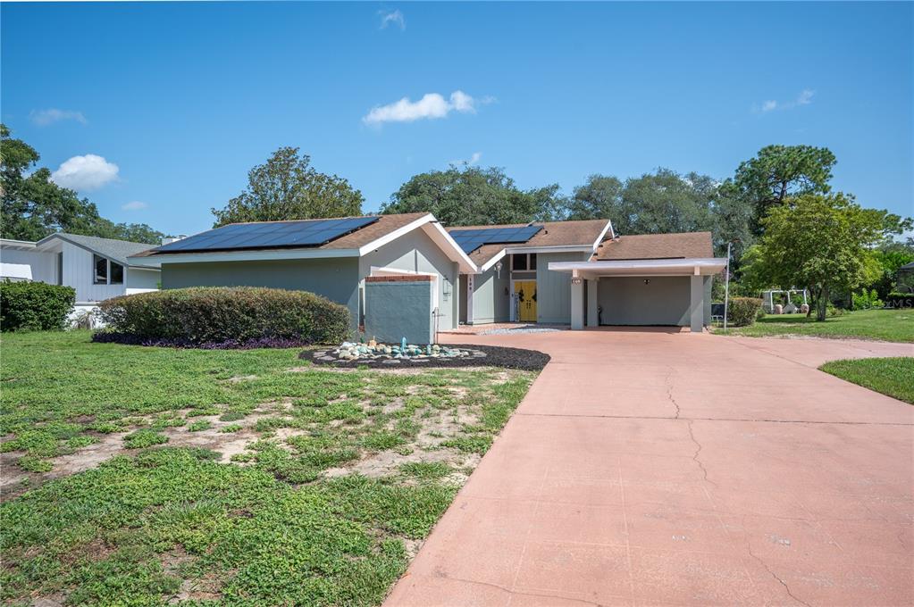A single-story house with a solar panel roof, a carport, and a paved driveway — 109 ARROWHEAD LANE, HAINES CITY, FL