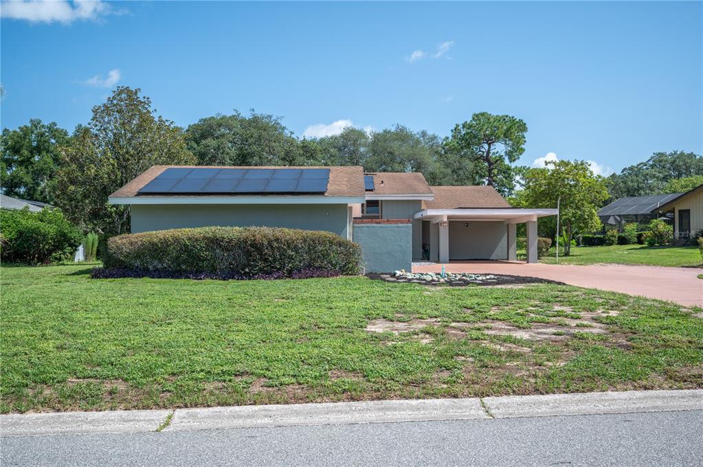 A single-story house with a solar panel array on the roof and a covered carport — 109 ARROWHEAD LANE, HAINES CITY, FL