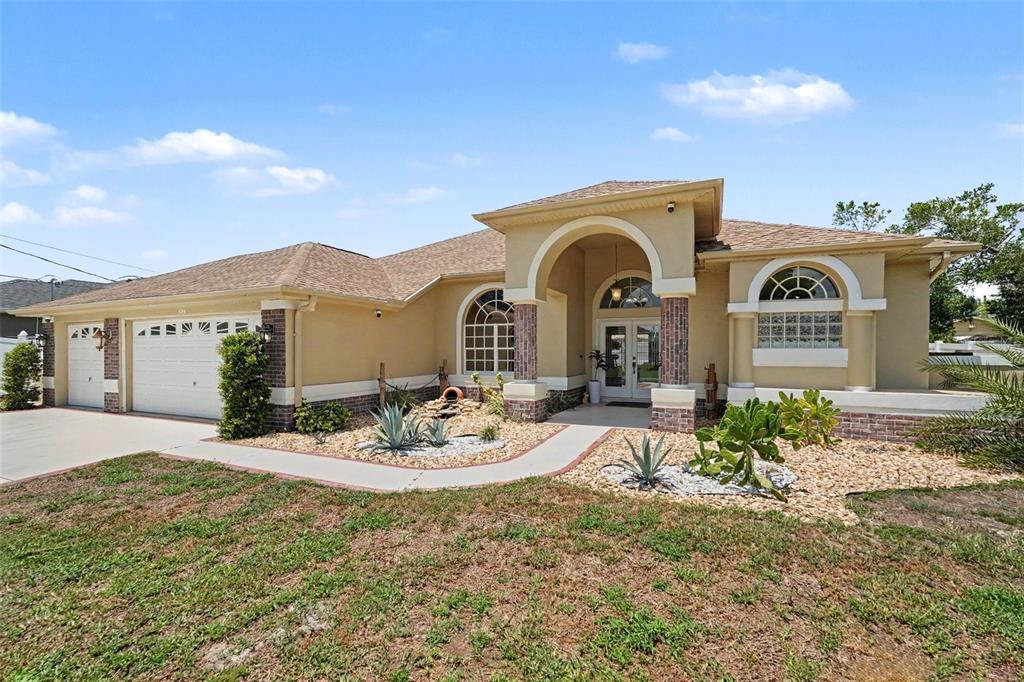 A single-story house with a tan stucco exterior, brick accents, and a paved driveway — 3944 LEMA DRIVE, SPRING HILL, FL
