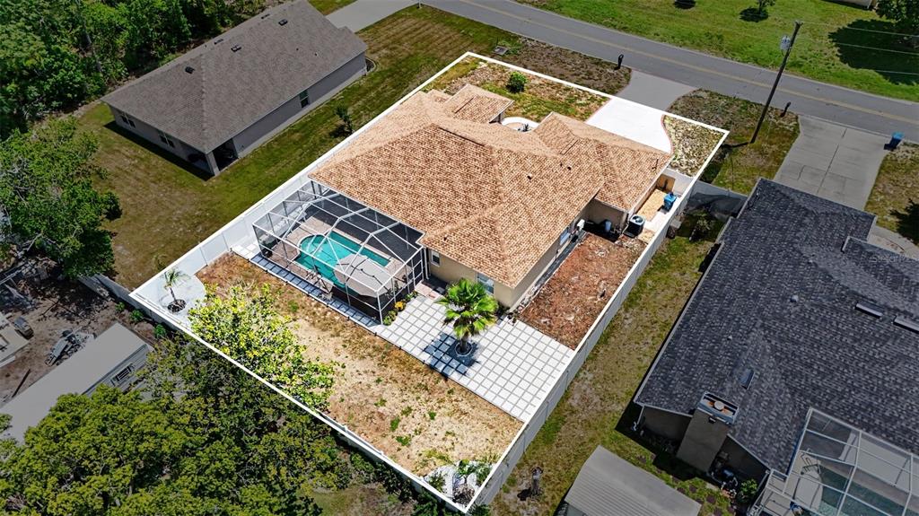 An aerial view shows a house with a fenced backyard, a pool enclosure, and patio — 3944 LEMA DRIVE, SPRING HILL, FL