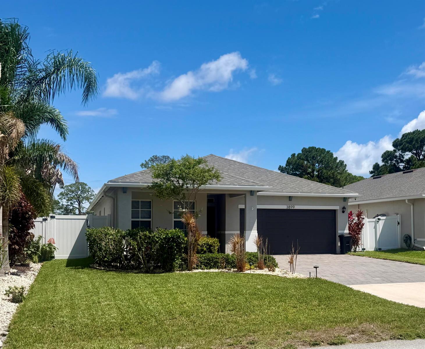 A single-story house with a gray roof, tan siding, and a dark garage door — 3899 SE Lee Street, Stuart FL 34997, STUART, FL